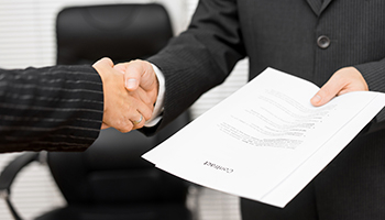 Businessman with contract in his hand is handshaking with business partner